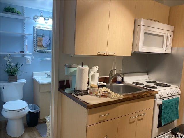 kitchen featuring light brown cabinetry, sink, wood-type flooring, and white appliances