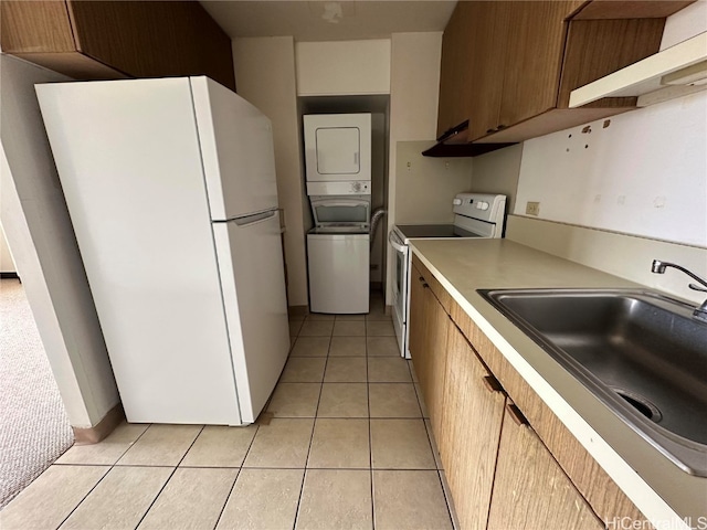 kitchen with sink, white appliances, stacked washer and dryer, and light tile patterned floors