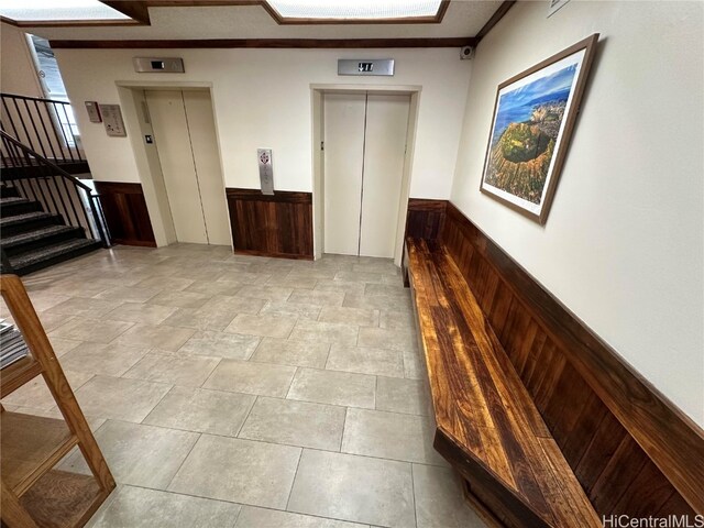 hall featuring elevator, crown molding, and wood walls