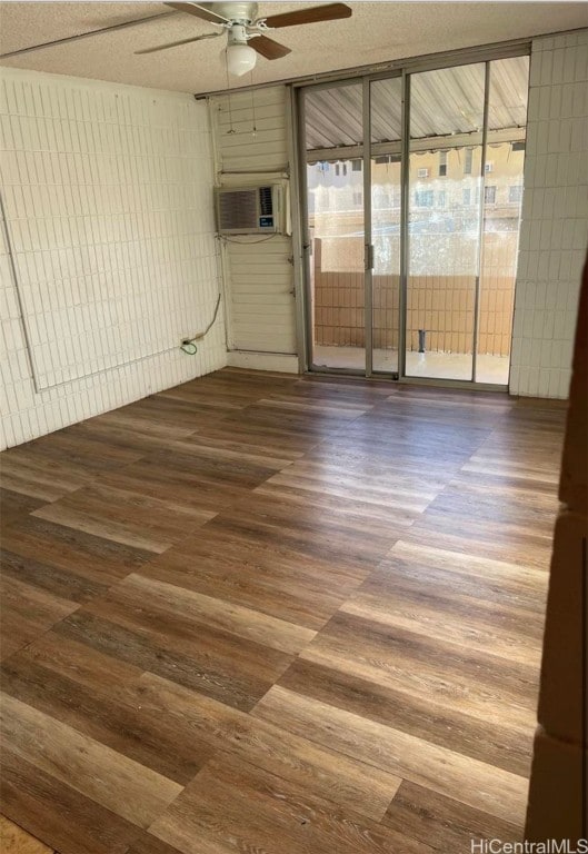 empty room with ceiling fan, cooling unit, and hardwood / wood-style flooring