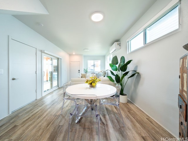 dining area with an AC wall unit and light hardwood / wood-style flooring