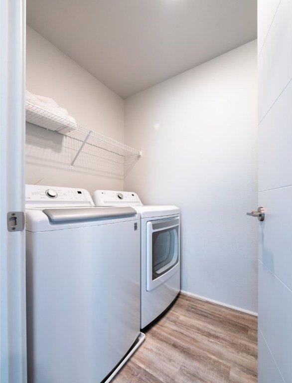 clothes washing area featuring washing machine and clothes dryer and light hardwood / wood-style flooring