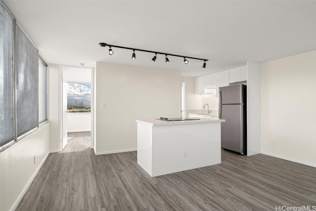 kitchen featuring stainless steel refrigerator, sink, light hardwood / wood-style flooring, track lighting, and white cabinets