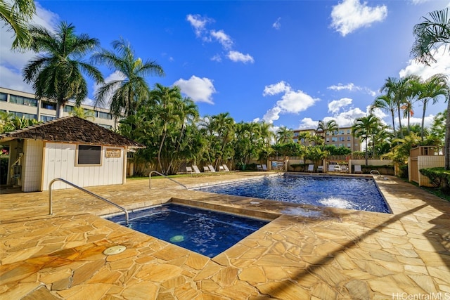 view of swimming pool with an outdoor structure, a patio, and a hot tub