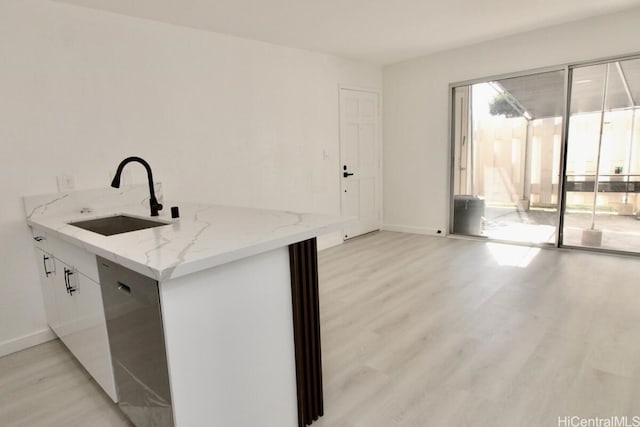 kitchen featuring white cabinets, light hardwood / wood-style floors, light stone counters, and sink