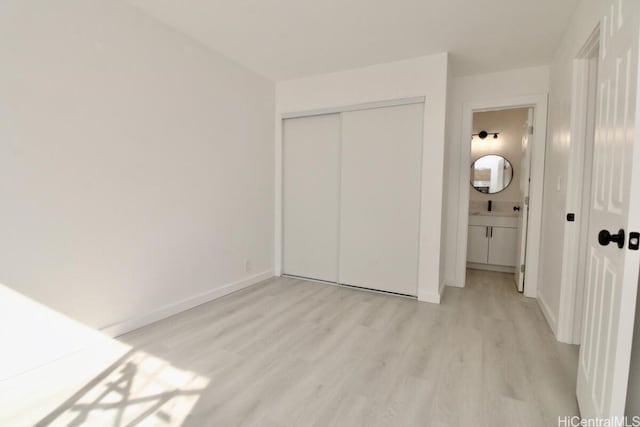 unfurnished bedroom with light hardwood / wood-style flooring, ensuite bath, and a closet