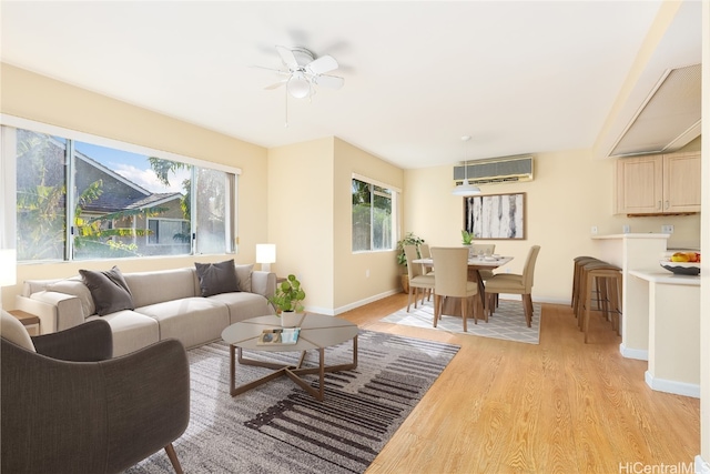 living room with light hardwood / wood-style flooring, an AC wall unit, and ceiling fan