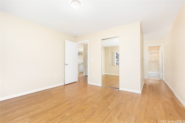 unfurnished bedroom with ensuite bathroom and light wood-type flooring