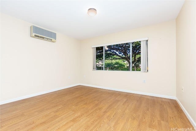 spare room featuring light wood-type flooring and a wall unit AC