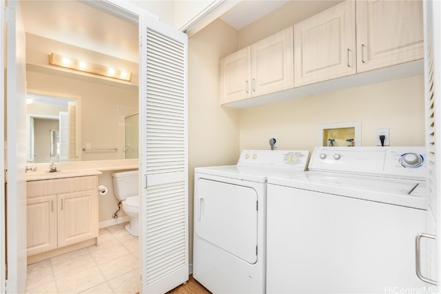 washroom with light tile patterned floors, washer and clothes dryer, and sink