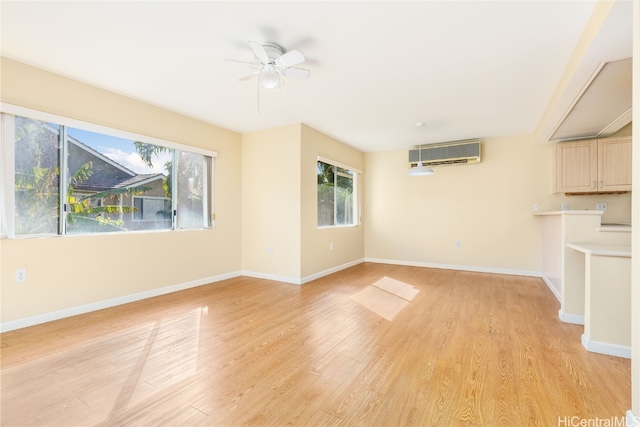 unfurnished living room with light wood-type flooring, a wall unit AC, and ceiling fan