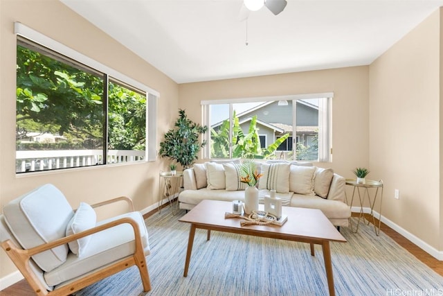 sitting room with wood finished floors, a ceiling fan, and baseboards