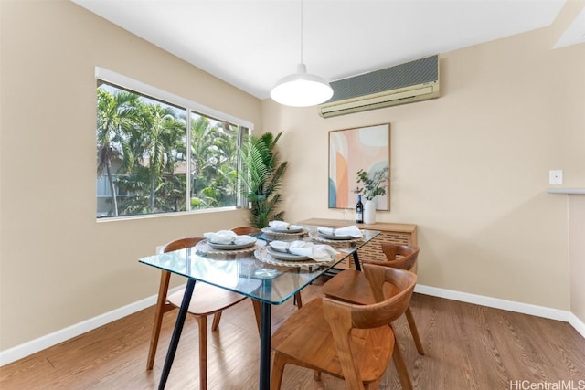 dining area with baseboards, wood finished floors, and a wall mounted air conditioner