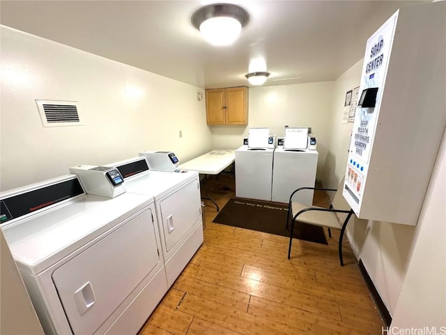 washroom with washer and clothes dryer and light wood-type flooring