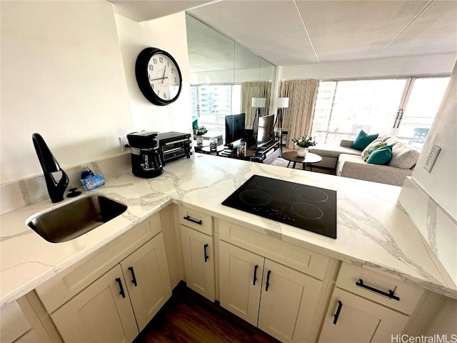 kitchen featuring plenty of natural light, light stone counters, and black electric cooktop