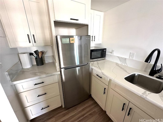 kitchen featuring stainless steel appliances, sink, dark wood-type flooring, and light stone counters