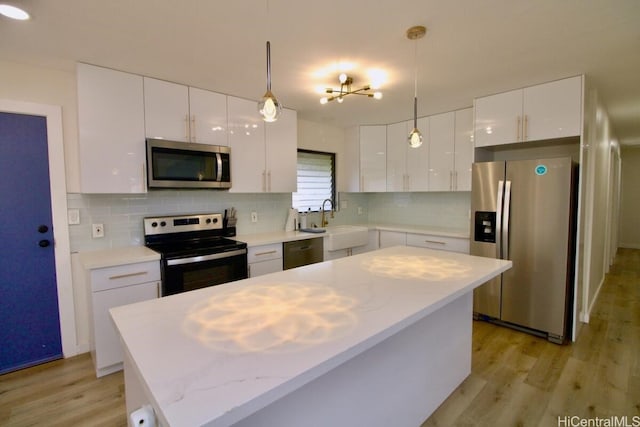 kitchen featuring white cabinetry, hanging light fixtures, a kitchen island, and stainless steel appliances