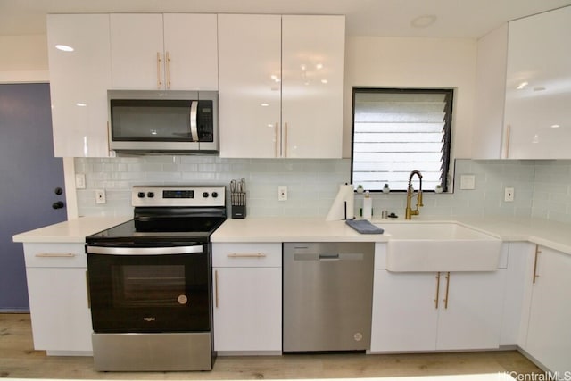 kitchen featuring appliances with stainless steel finishes, tasteful backsplash, white cabinetry, and sink