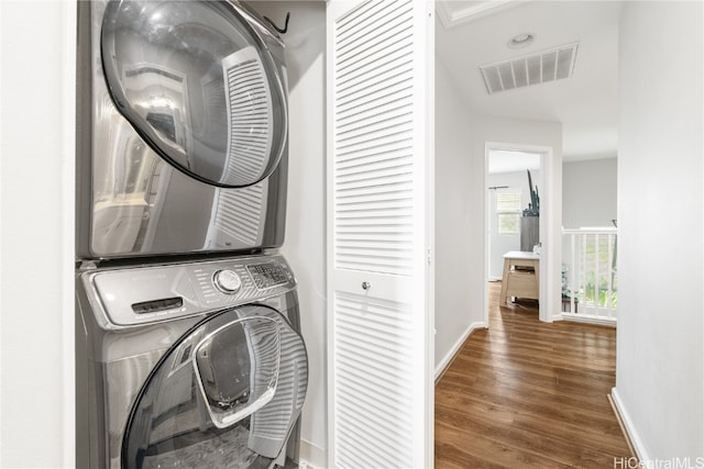 laundry area featuring dark hardwood / wood-style floors and stacked washer / dryer