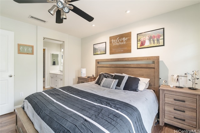 bedroom with ensuite bath, ceiling fan, and dark hardwood / wood-style flooring