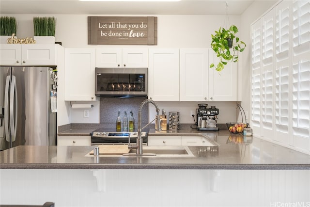 kitchen with white cabinets, backsplash, stainless steel appliances, and sink