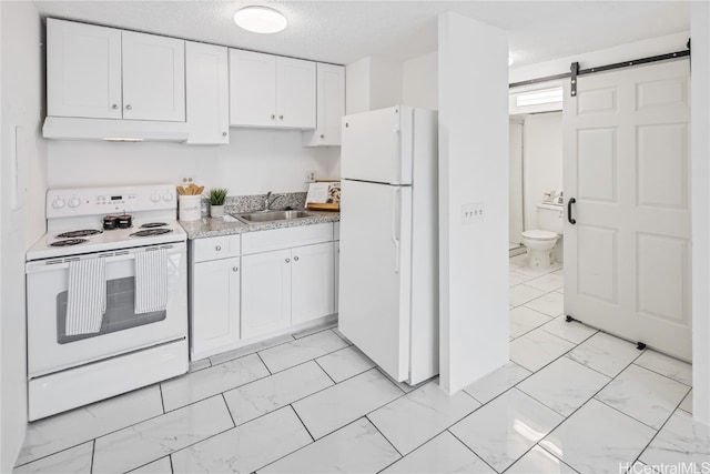 kitchen featuring white appliances, a barn door, white cabinetry, and sink