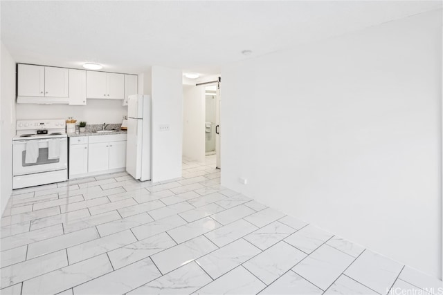 kitchen with a barn door, white cabinetry, sink, and white appliances