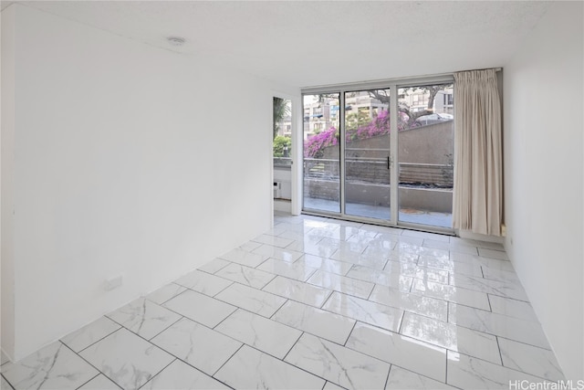 unfurnished room featuring a wall of windows and a textured ceiling