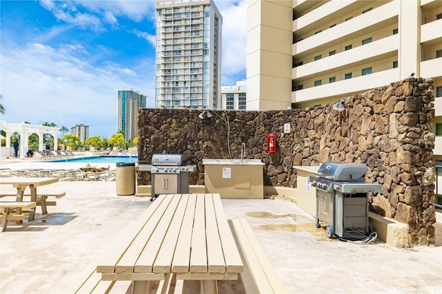 view of patio featuring a pergola, grilling area, and a community pool