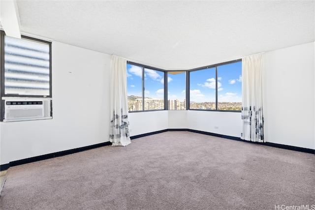 carpeted spare room featuring a textured ceiling, plenty of natural light, and cooling unit