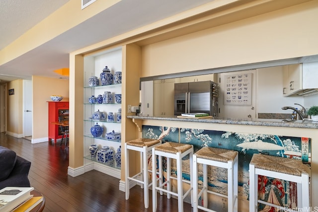 kitchen with light stone countertops, stainless steel fridge with ice dispenser, dark hardwood / wood-style floors, and sink