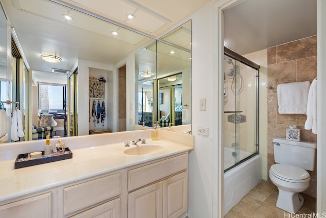 full bathroom with vanity, shower / bath combination with glass door, tile patterned flooring, toilet, and tile walls