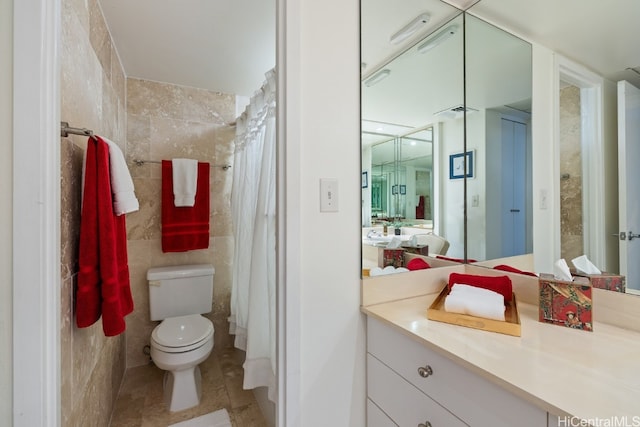 bathroom featuring a shower with shower curtain, tile patterned floors, vanity, tile walls, and toilet