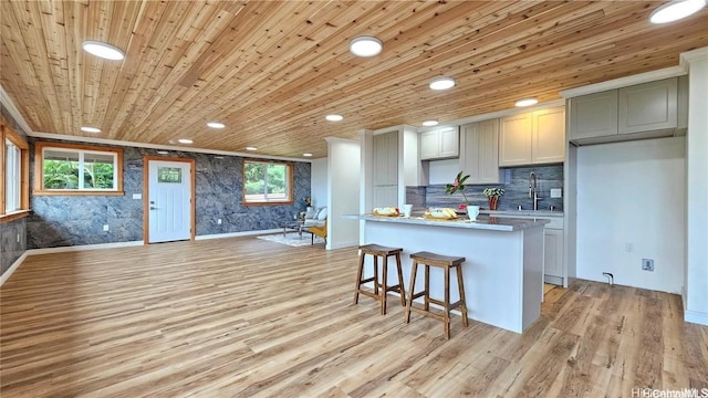 kitchen with a kitchen island, recessed lighting, a sink, light wood-style floors, and wooden ceiling