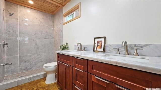 full bath with double vanity, toilet, a tile shower, and a sink