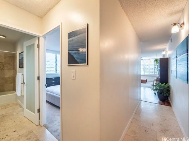 corridor with a textured ceiling and a wealth of natural light