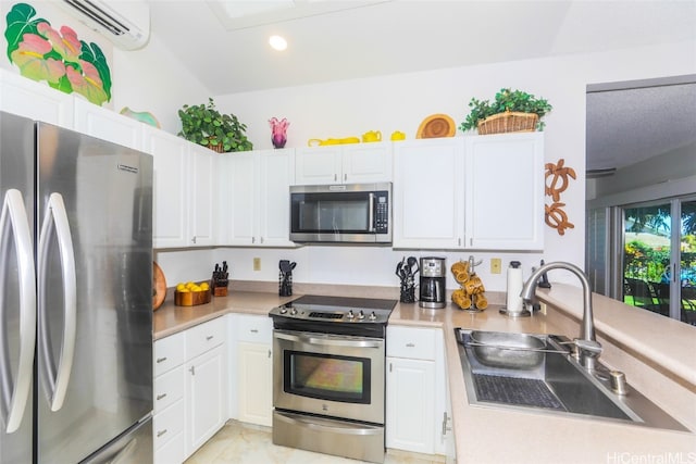 kitchen with white cabinets, appliances with stainless steel finishes, a wall mounted AC, and sink