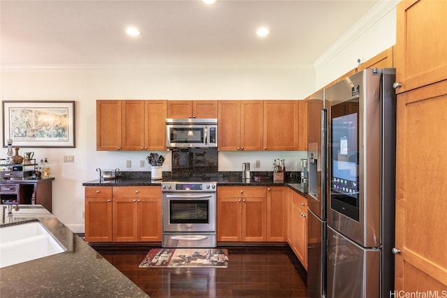 kitchen featuring sink, stainless steel appliances, dark hardwood / wood-style flooring, crown molding, and dark stone counters