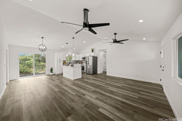 unfurnished living room featuring ceiling fan with notable chandelier, dark wood-type flooring, and vaulted ceiling