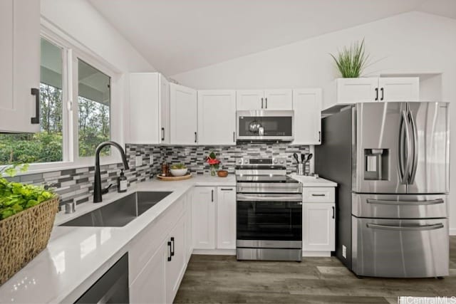 kitchen featuring appliances with stainless steel finishes, white cabinetry, lofted ceiling, and sink