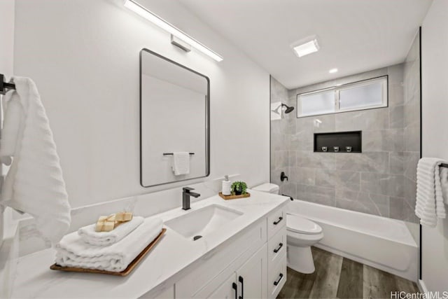 full bathroom with vanity, hardwood / wood-style floors, tiled shower / bath combo, and toilet