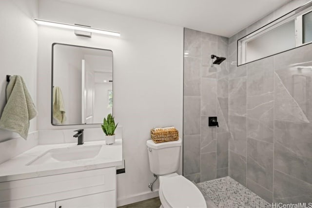 bathroom featuring vanity, toilet, and a tile shower