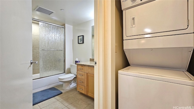 clothes washing area featuring light tile patterned flooring and stacked washing maching and dryer