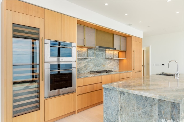 kitchen featuring light stone countertops, appliances with stainless steel finishes, light wood-type flooring, and sink