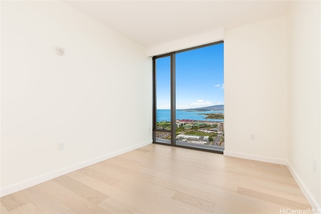 empty room with light hardwood / wood-style floors, a water view, and floor to ceiling windows