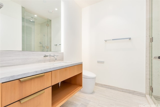 bathroom featuring vanity, a shower with shower door, and toilet