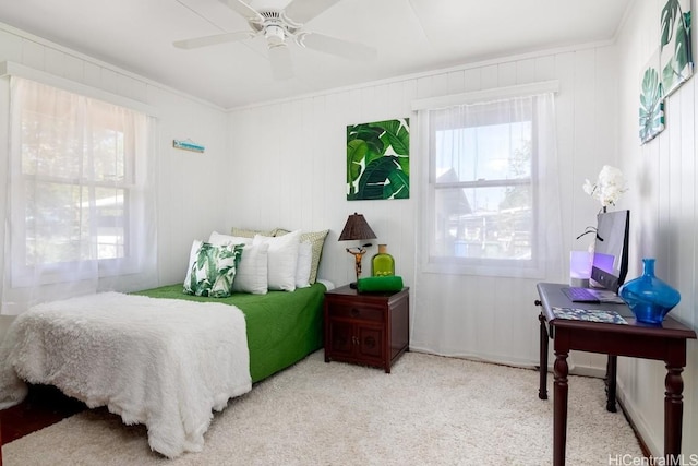 carpeted bedroom featuring ceiling fan, wood walls, and crown molding