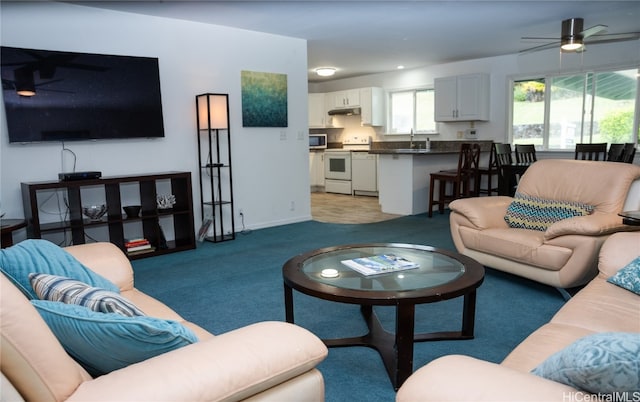 living room featuring ceiling fan, light colored carpet, and sink