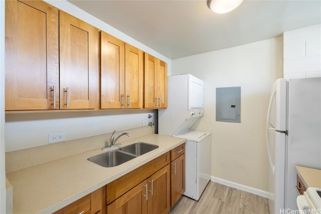 laundry room with electric panel, sink, stacked washer and dryer, and light hardwood / wood-style flooring