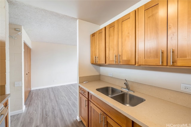 kitchen with sink, light hardwood / wood-style floors, and a textured ceiling